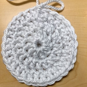 May include: White crocheted circle with a textured surface.