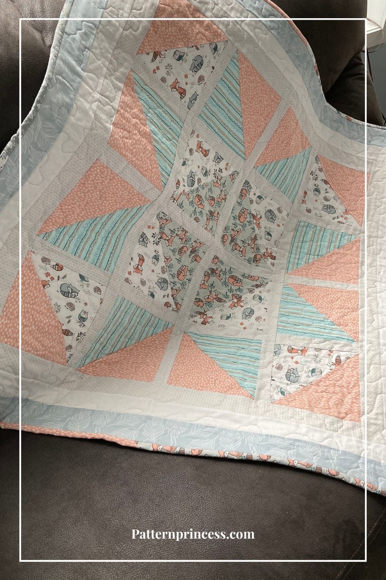 Puede incluir: Una colcha para beb&eacute; con un patr&oacute;n de estrella en forma de estallido en tonos de rosa, azul y blanco. La tela presenta un estampado de animales del bosque con zorros, mapaches y otras criaturas del bosque.