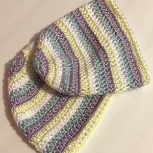 May include: A crocheted hat with stripes of white, light blue, purple, and yellow yarn.