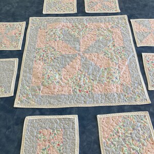 Peut inclure: Un ensemble de sets de table et de serviettes matelassés à motifs floraux dans des tons de rose, blanc et bleu. Les sets de table et les serviettes ont une bordure blanche.
