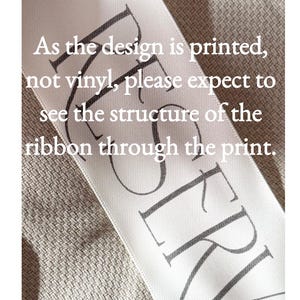 Puede incluir: Una cinta de sat&eacute;n blanca con texto impreso en negro que dice: As the design is printed, not vinyl, please expect to see the structure of the ribbon through the print. La cinta tiene una textura tejida visible y la palabra RESERVED es parcial.