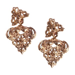 Peut inclure: Une paire de boucles d'oreilles en filigrane dorées avec un design délicat et complexe. Les boucles d'oreilles sont en métal et ont une forme pendante.
