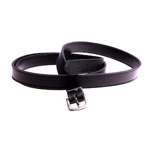 Peut inclure: Une ceinture en cuir noir avec une boucle argentée. La ceinture est pliée en deux et la boucle est visible.