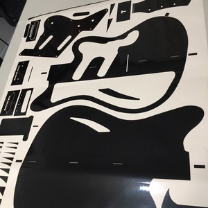 Puede incluir: Plantilla de guitarra en blanco y negro para construir una guitarra. La plantilla incluye el cuerpo, el m&aacute;stil y otras partes de la guitarra.