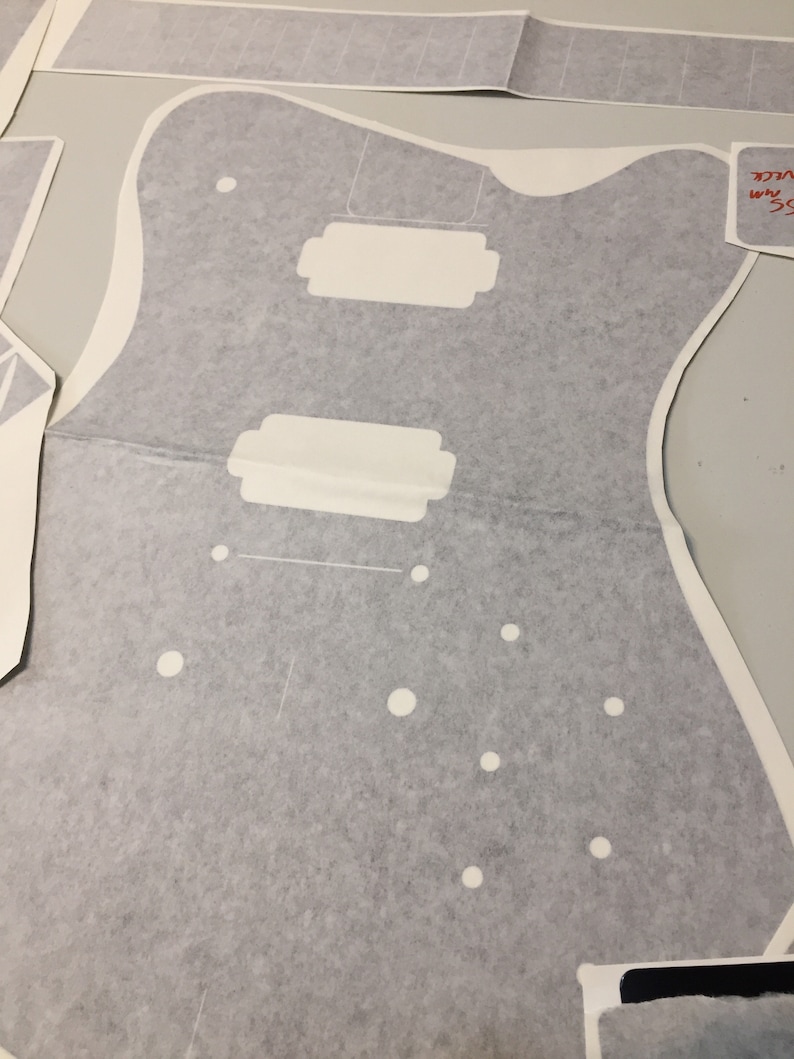 May include: A grey guitar body template with white circles and rectangular cutouts. The template is labelled "35 mm" and "SCALE".