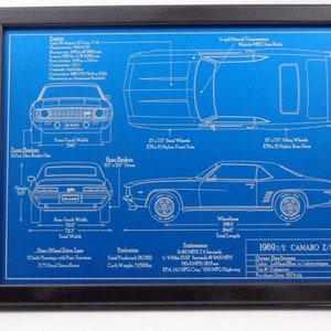May include: Framed blueprint of a 1969 1/2 Camaro Z/28 in a black frame. The blueprint is on a blue background with white lines and text detailing the car's specifications, including dimensions in inches and performance metrics.