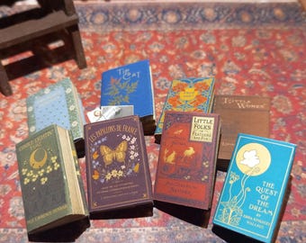 May include: A collection of miniature books with various titles and designs. The books feature colors like blue, green, brown, and purple. Some titles include "The Cat", "Little Folks", and "The Quest of the Dream".