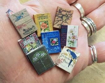 May include: A collection of miniature books with various titles, including "Marvels Pond Life", "The Language of Flowers", "Birdcraft", "By-Hedgerow Mead & Pool", "Familiar Garden Flowers", and "Speaking Parrots".