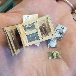 K&ouml;nnte beinhalten: Ein kleines, vintage Fotoalbum mit mehreren Schwarzwei&szlig;fotos von Personen. Das Album ist ge&ouml;ffnet und die Fotos sind sichtbar. Das Album wird in einer Hand gehalten.