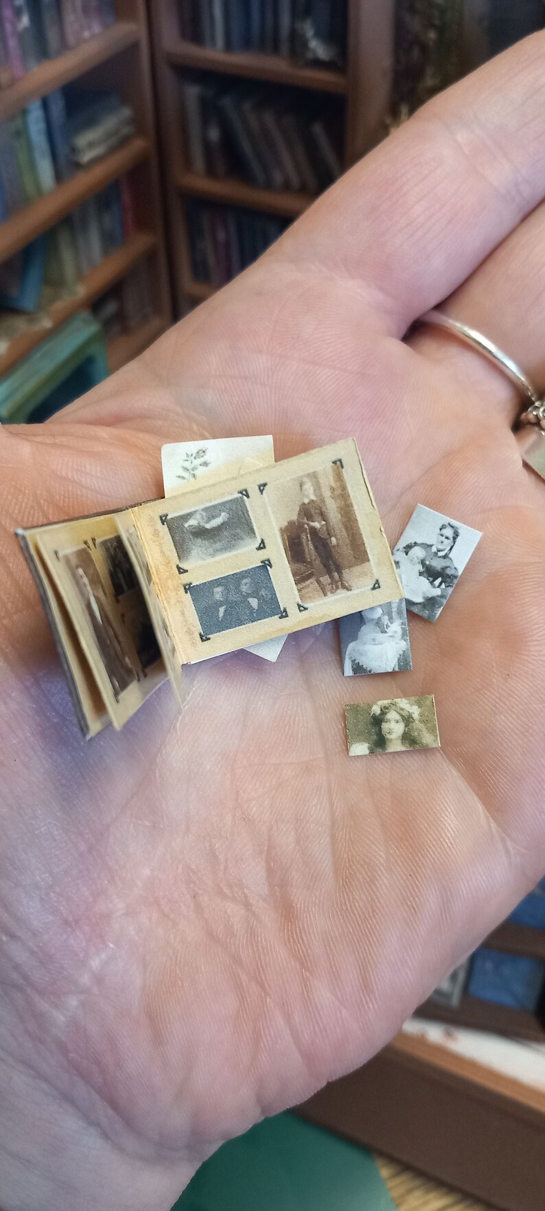 K&ouml;nnte beinhalten: Ein kleines, vintage Fotoalbum mit mehreren Schwarzwei&szlig;fotos von Personen. Das Album ist ge&ouml;ffnet und die Fotos sind sichtbar. Das Album wird in einer Hand gehalten.