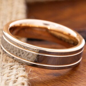 Op de afbeelding: Een roségouden ring van wolframcarbide met twee gepolijste groeven. De ring is een eenvoudig ontwerp met een geborstelde afwerking.