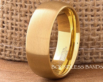 May include: A gold tungsten carbide ring with a brushed finish and a polished edge. The ring is engraved with "Tungsten Carbide" on the inside. The ring is on a burlap background.