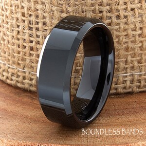 May include: A black beveled edge tungsten carbide ring. The ring is polished and has a shiny finish.