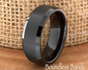 May include: A black ring with a brushed metal finish and a polished interior. The ring is set against a textured background and the text "Boundless Bands" is visible.