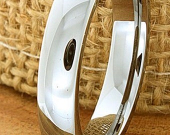 May include: A silver-toned wedding band with a polished finish. The band is smooth and has a rounded edge.