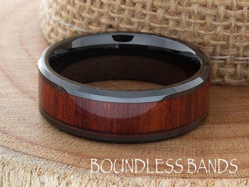 Op de afbeelding: Een zwarte keramische ring met een rode houten inlay. De ring is afgeschuind en heeft een gepolijste afwerking. Boundless Bands.