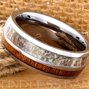 May include: A silver tungsten ring with a brown wood inlay and a white antler inlay.