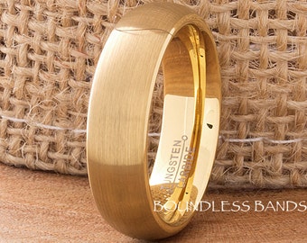 May include: A gold tungsten carbide ring with a brushed finish. The ring is engraved with "Tungsten Carbide".
