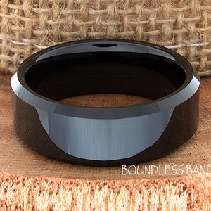 May include: A black ceramic wedding band with a beveled edge. The band has a polished finish and is made of durable tungsten carbide.