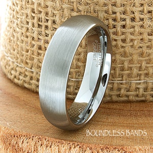 Op de afbeelding: Een geborstelde zilveren ring van wolframcarbide met een afgeschuinde rand. De ring is gegraveerd met "Tungsten Carbide".