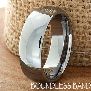 Puede incluir: Una banda de boda de carburo de tungsteno plateada con un acabado pulido. La banda tiene 8 mm de ancho y un borde biselado.