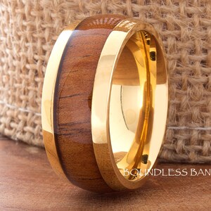 Puede incluir: Un anillo de madera y oro con una banda dorada. El anillo está hecho de madera y metal. La madera es de color marrón oscuro y el metal es de color dorado brillante. El anillo es un diseño simple y sería una excelente alianza.