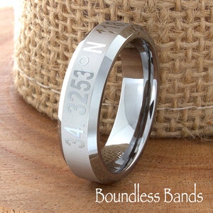May include: A silver tungsten carbide ring with a beveled edge and engraved coordinates, "34.3253° N 118.180°".