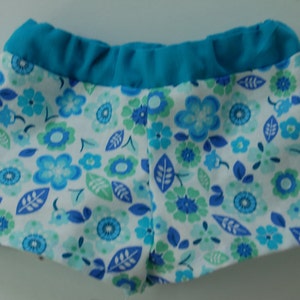 May include: Blue and white floral print swim shorts with a turquoise waistband.