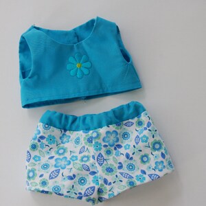 May include: A two-piece doll outfit with a sleeveless turquoise top and a white and blue floral print bottom.