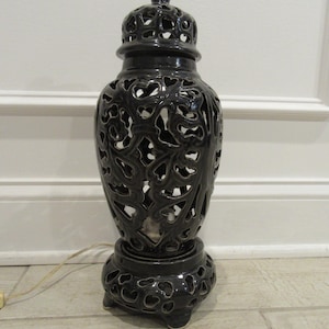 May include: A dark charcoal gray ceramic table lamp featuring an intricate openwork lattice design throughout the body, base, and removable lid. The lamp has a glossy finish and includes a thin white electrical cord extending from the base.