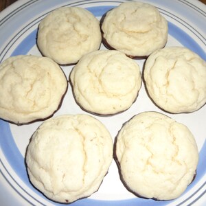 May include: A plate of six round cookies with a chocolate coating on the bottom. The cookies are light brown and have a slightly rough texture.