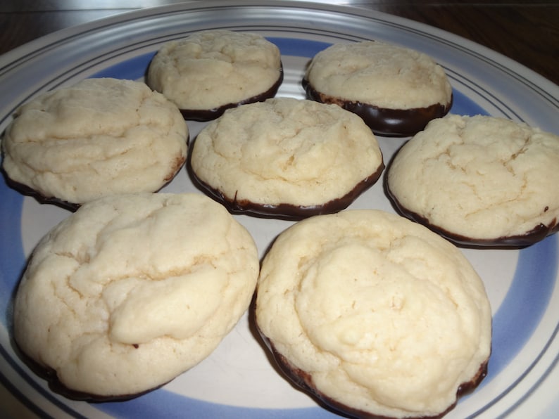 May include: A plate of six round cookies with a chocolate glaze on the bottom. The cookies are light brown and have a slightly rough texture.