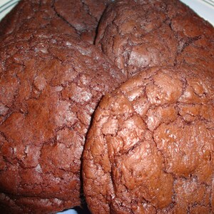 May include: Close-up of four chocolate chip cookies on a blue and white plate. The cookies are brown and have a slightly crispy texture.