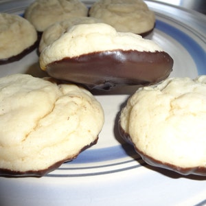 May include: A plate of six cookies, some with chocolate frosting. The cookies are round and have a light brown color. The plate has a blue and white striped pattern.