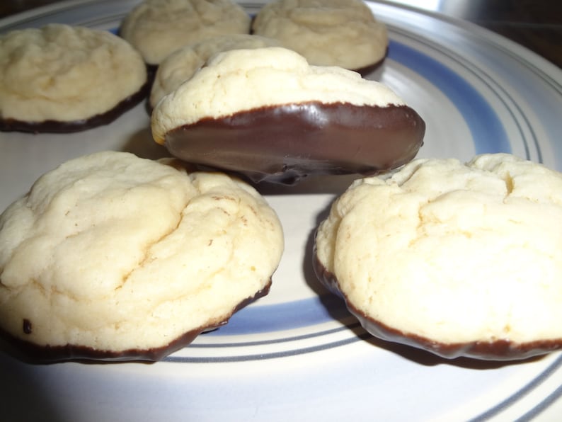 May include: A plate of six cookies, some with chocolate frosting. The cookies are round and have a light brown color. The plate has a blue and white striped pattern.