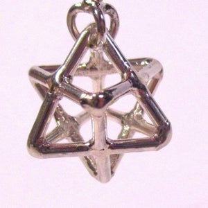 Puede incluir: Un colgante de plata en forma de estrella geométrica con un bucle en la parte superior para sujetarlo a una cadena.