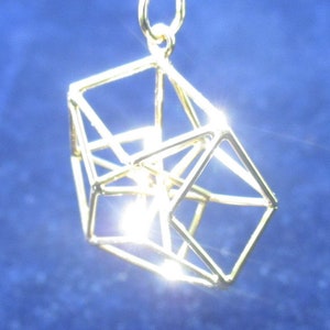 Może przedstawiać: Złoty naszyjnik z geometrycznym wisiorem w kształcie trójwymiarowej kostki.