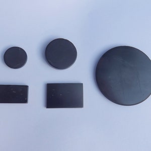 May include: Five black round and rectangular shaped magnets of various sizes.