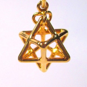 Peut inclure: Un pendentif en métal doré en forme d'étoile tridimensionnelle. Le pendentif est fait de fil et a un design géométrique.