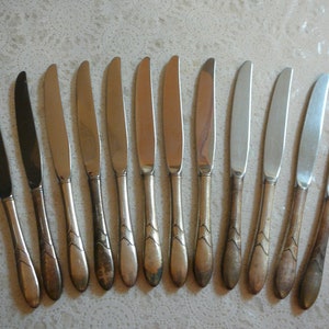 May include: A set of twelve silver dinner knives with ornate handles. The knives have a polished finish and are in good condition.