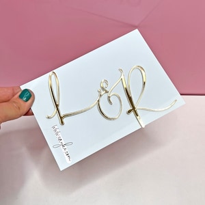 May include: A white card with gold foil letters spelling "L & R" and the text "withlovejake.com" printed in black.
