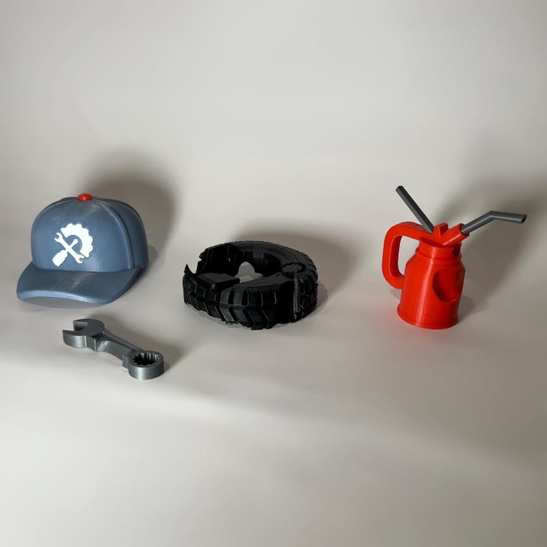 May include: A collection of mechanic-themed items. Includes a blue baseball cap with a gear and wrench logo, a black tire, a silver wrench, and a red oil can with gray spouts. The items are arranged on a white surface.