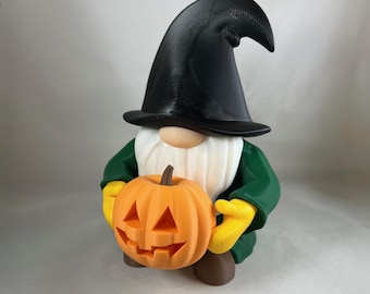 May include: A Halloween gnome figurine wearing a black witch hat, green jacket, yellow gloves, and brown shoes. The gnome is holding an orange carved pumpkin. The figurine has a white beard and a tan nose.