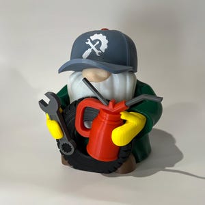 May include: A whimsical gnome figurine dressed as a mechanic, wearing a blue cap with a wrench logo. The gnome holds a wrench, a red oil can, and a tire. The gnome's outfit includes a green jacket and yellow gloves.