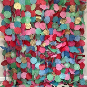 May include: A colourful garland made of paper circles in shades of red, blue, green, and gold. The circles are strung together on a white string and hang in a cascading pattern.