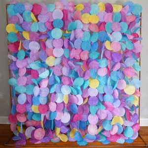 May include: A backdrop made of colorful paper circles strung together on a copper frame. The circles are in shades of pink, purple, blue, and yellow.