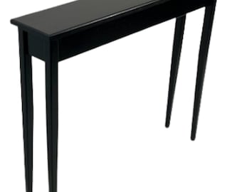 May include: A black console table with a long, rectangular top and two slender legs. The table is made of wood and has a simple, modern design.