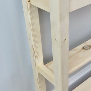 May include: A light wood console table with two shelves. The table has a simple design with straight lines and a natural finish.
