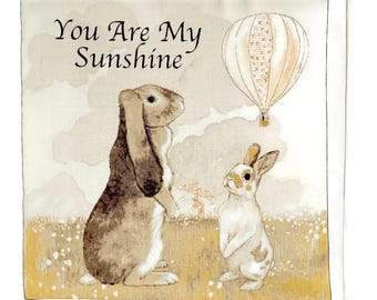 May include: A card with a light brown background featuring two rabbits and a hot air balloon. The text "You Are My Sunshine" is printed in black at the top of the card.