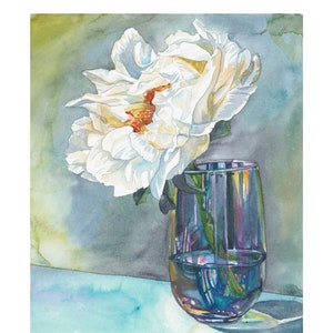 May include: A single white peony flower with a hint of orange in the center is in a clear glass vase with a purple iridescent tint. The vase is sitting on a light blue surface.